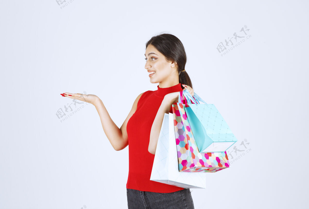 模特穿红衬衫的女孩 带着五颜六色的购物袋成人模特人