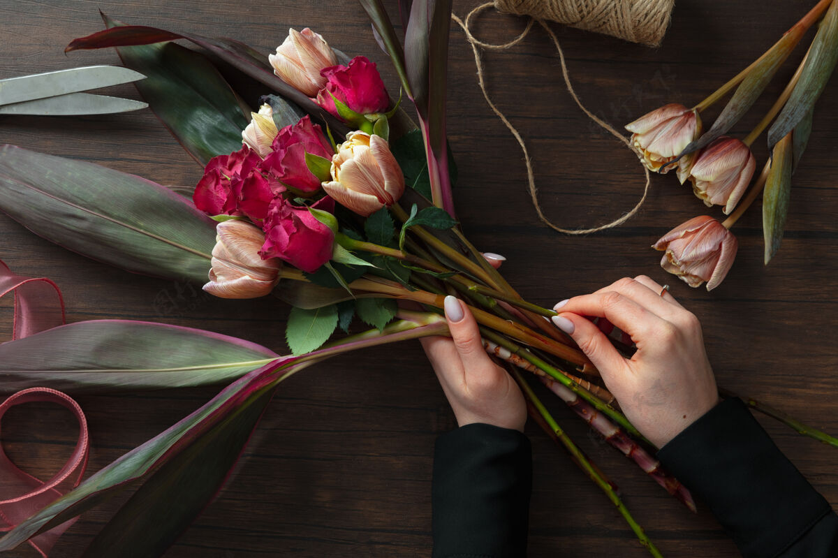 花店工作中的花店：妇女在木制背景上用不同的鲜花制作时尚的现代花束大师级在婚礼 母亲节 妇女节送给新娘的礼物浪漫的春季时尚激情玫瑰作品园艺女孩