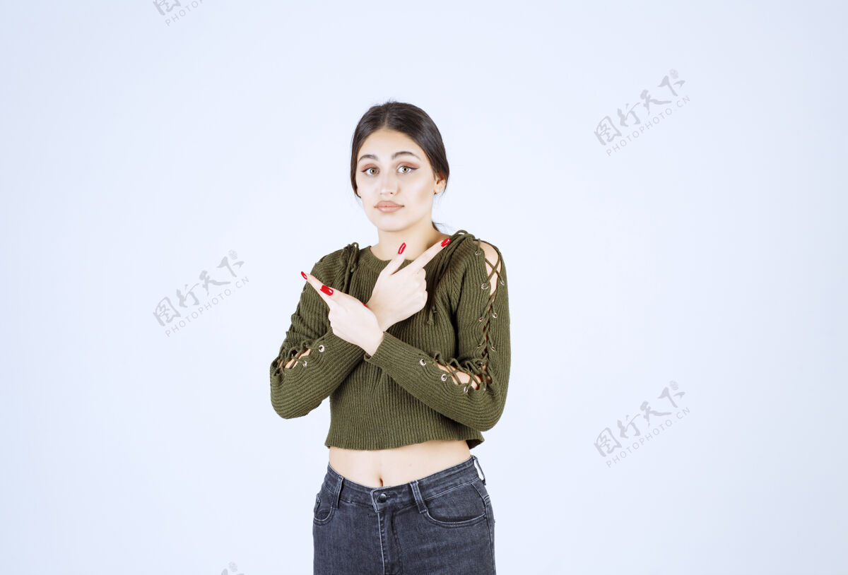 站在一边一个年轻的女模特站在一边用食指指着的照片模特目录女孩