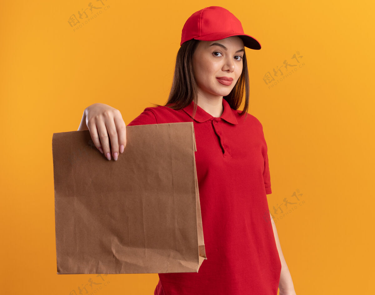 持有自信漂亮的女送货员穿着制服拿着纸包纸自信包装