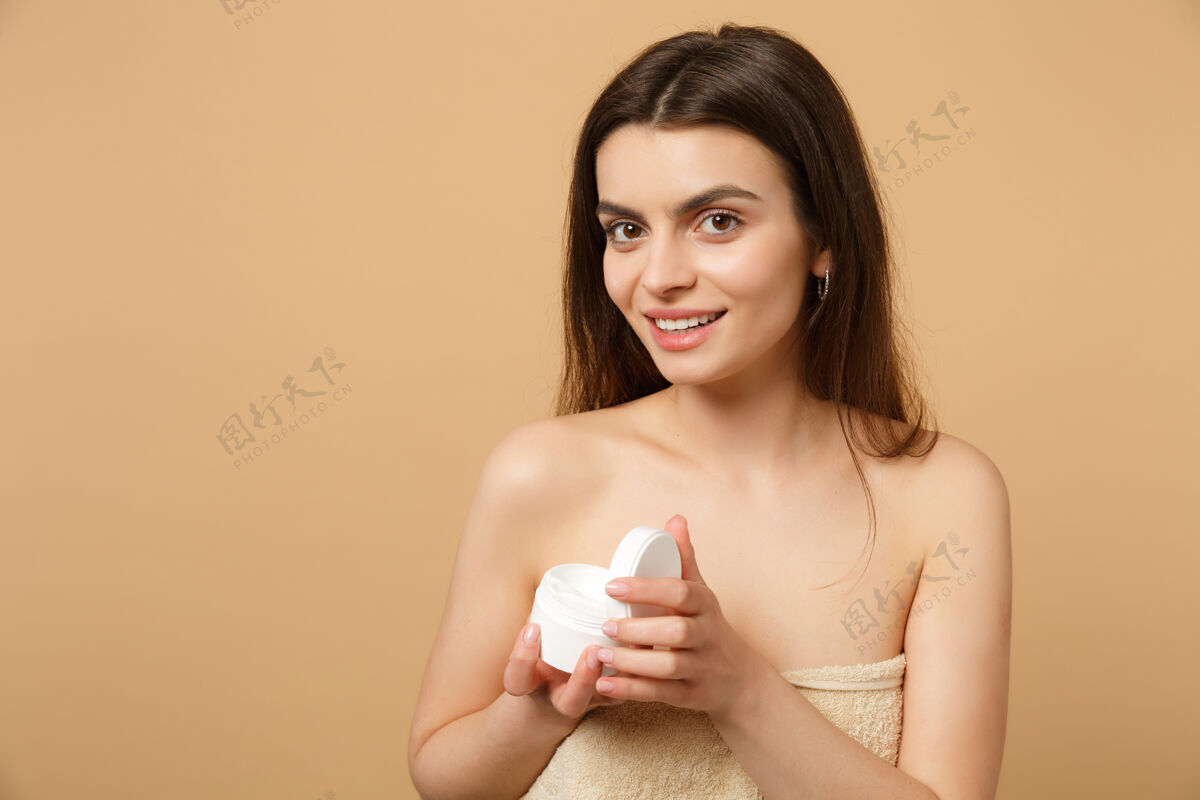 完美近景半裸体女人完美皮肤裸妆涂抹面霜隔离在米色粉彩墙上手肩膀保护