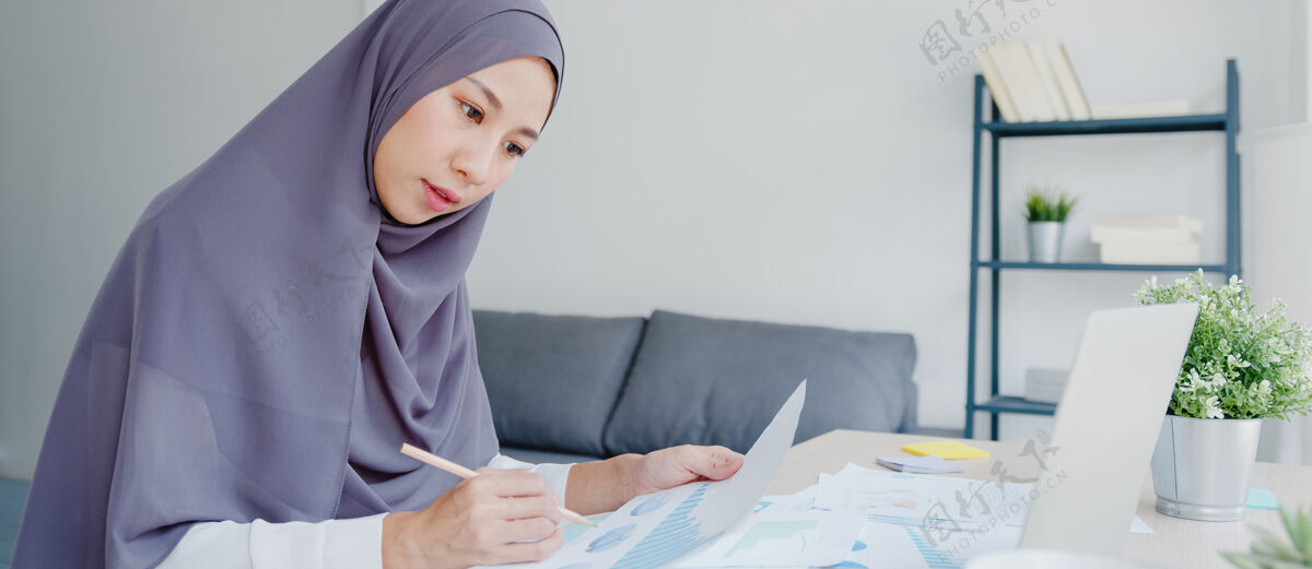 阿拉伯语美丽的亚洲穆斯林女士戴着头巾 穿着休闲服 在家里的客厅里使用笔记本电脑文化自由职业者印度人