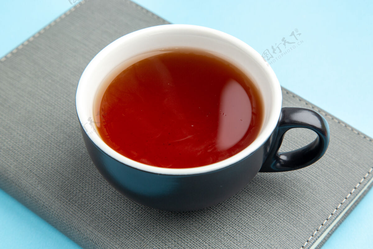 汤在蓝色表面的灰色笔记本上近距离观看一杯红茶视图杯子茶碟