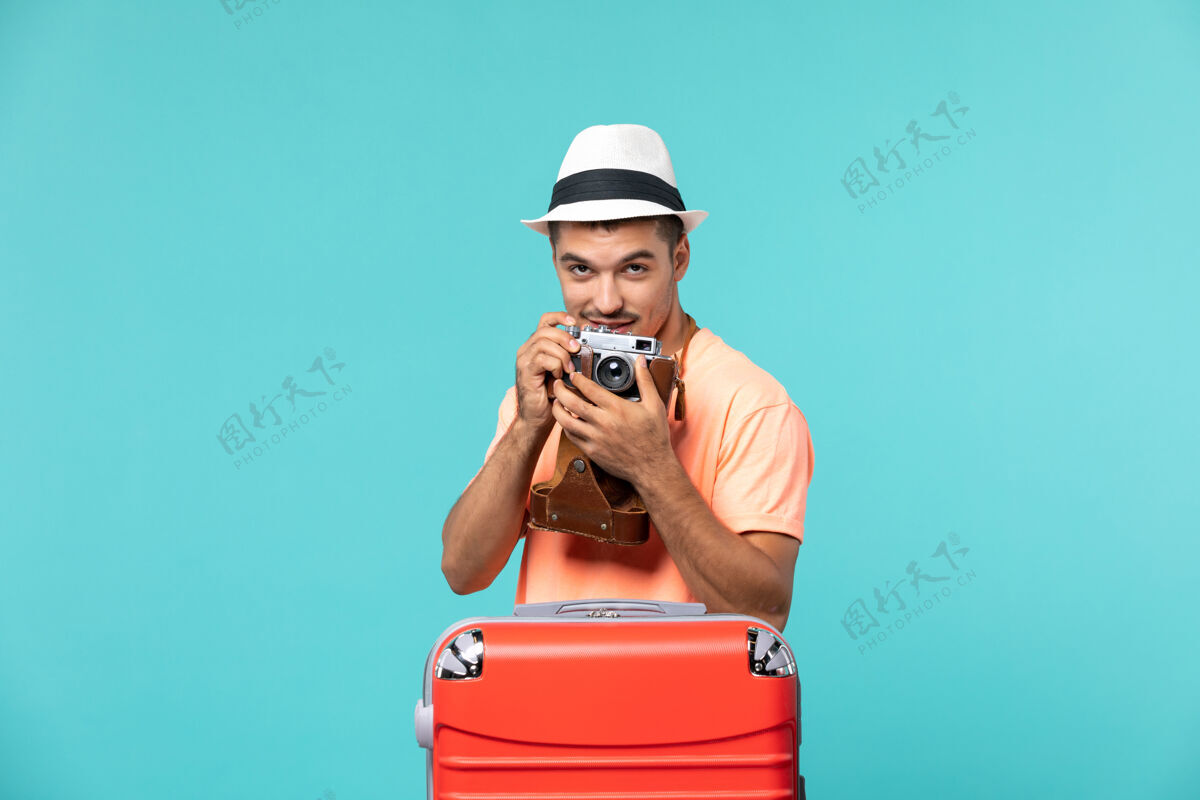 男性带着红色手提箱的度假男人用蓝色的相机拍照包人肖像