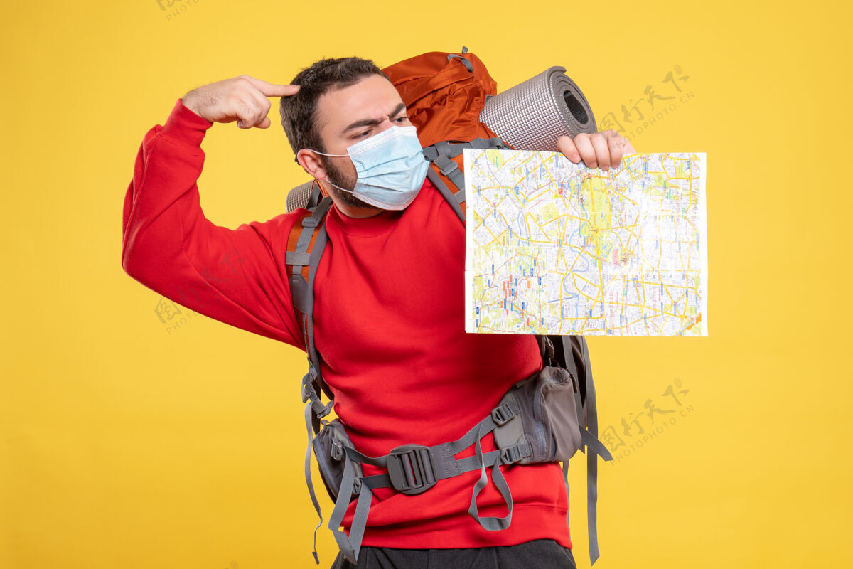 人顶视图年轻的思想旅行者家伙戴着医疗面具和背包举行黄色地图持有漂亮快乐