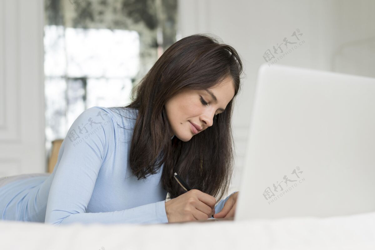 室内工作时躺在床上的女人设备笔记本电脑年轻人
