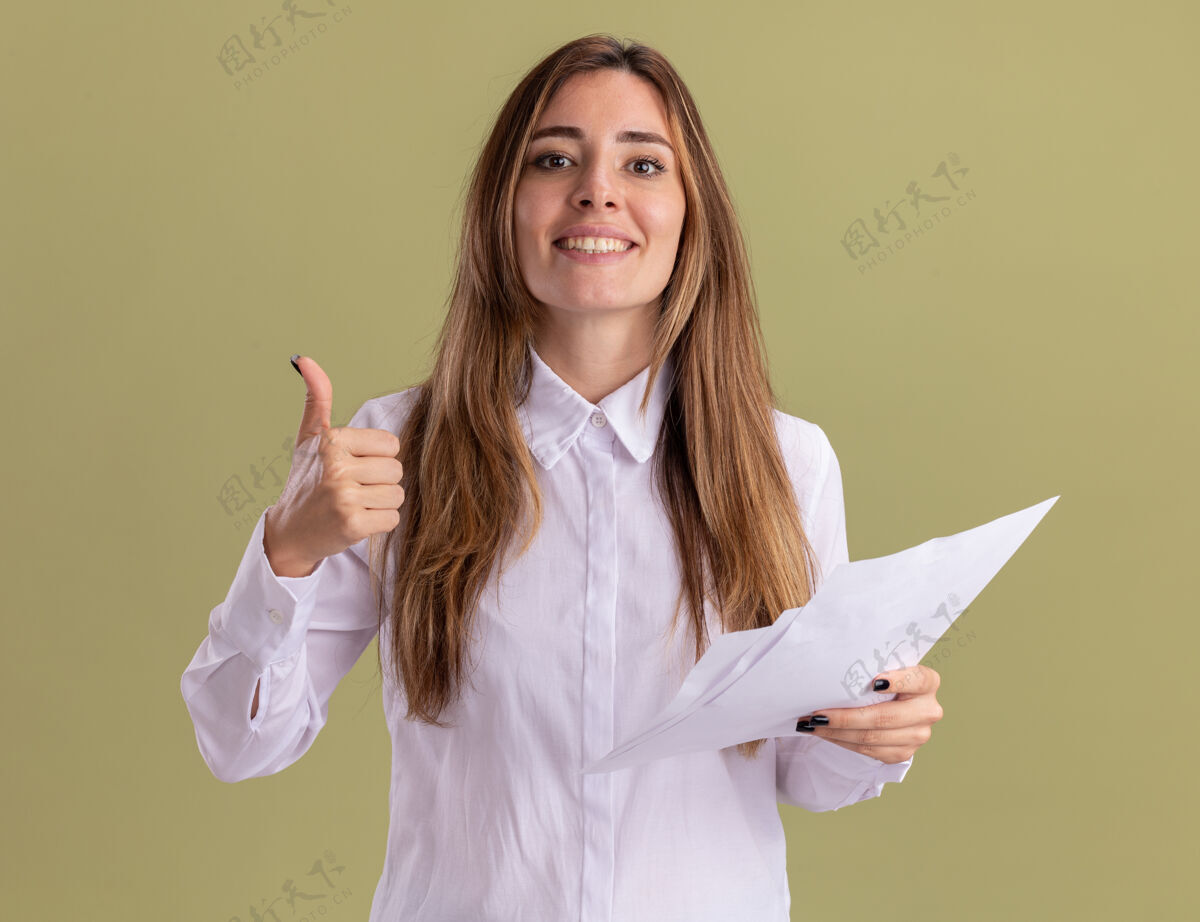 拇指年轻漂亮的白人女孩微笑着竖起大拇指 拿着空白的纸页举行女孩微笑