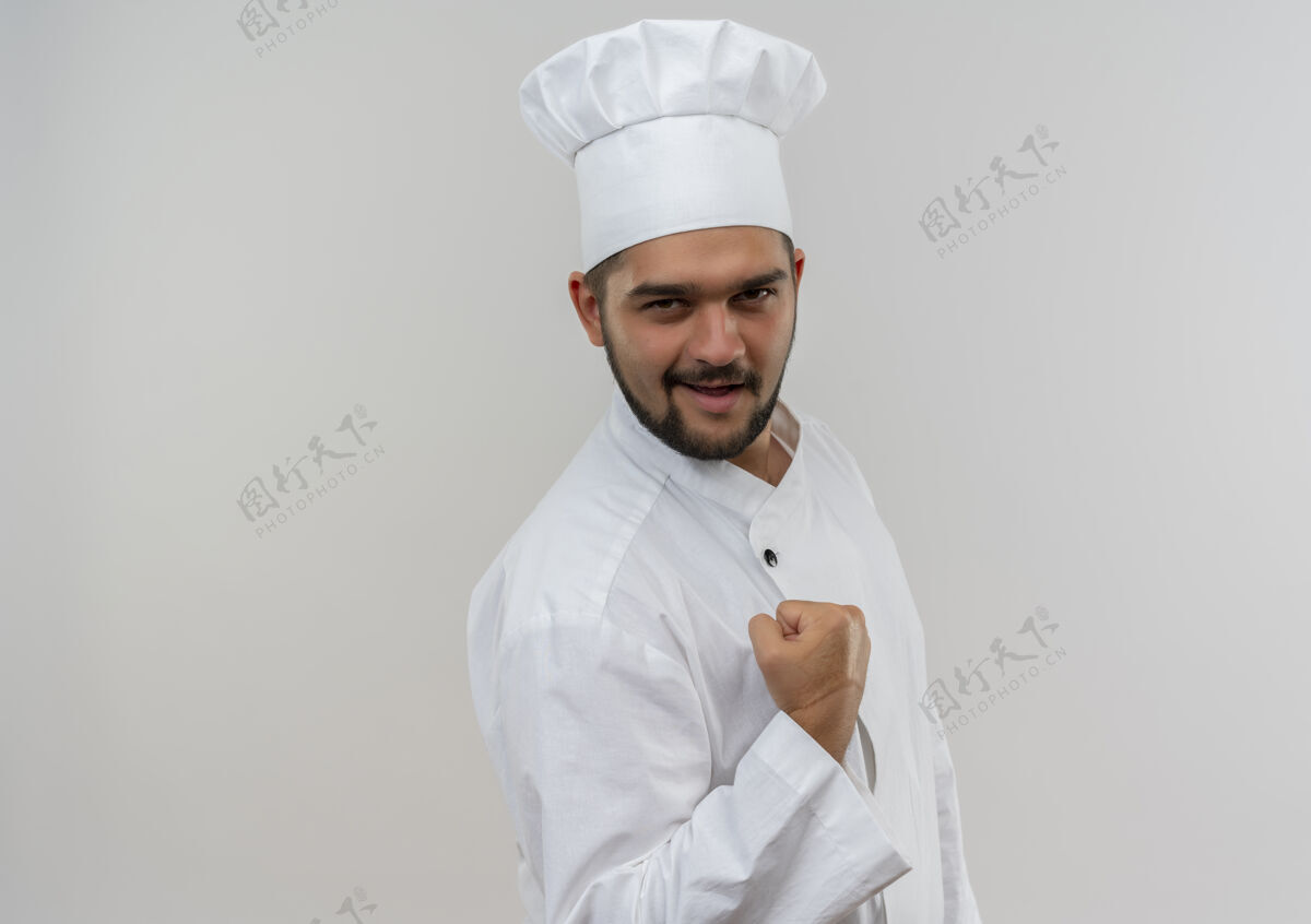 握紧快乐的年轻男厨师穿着厨师制服紧握拳头隔离在白色的墙壁与复制空间制服快乐年轻