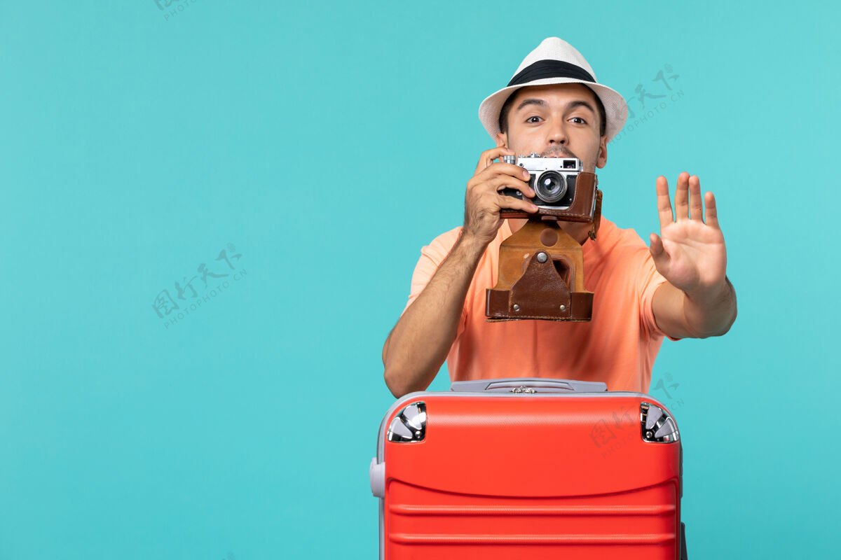 人带着红色手提箱和蓝色相机的度假男人肖像包成人