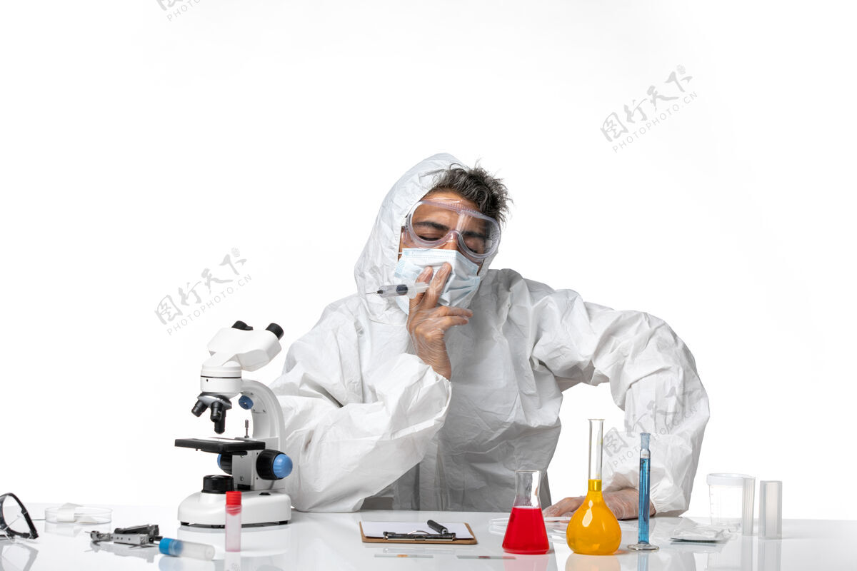 视图男医生穿着防护服 带着无菌口罩 拿着白色的注射器灭菌套装医院