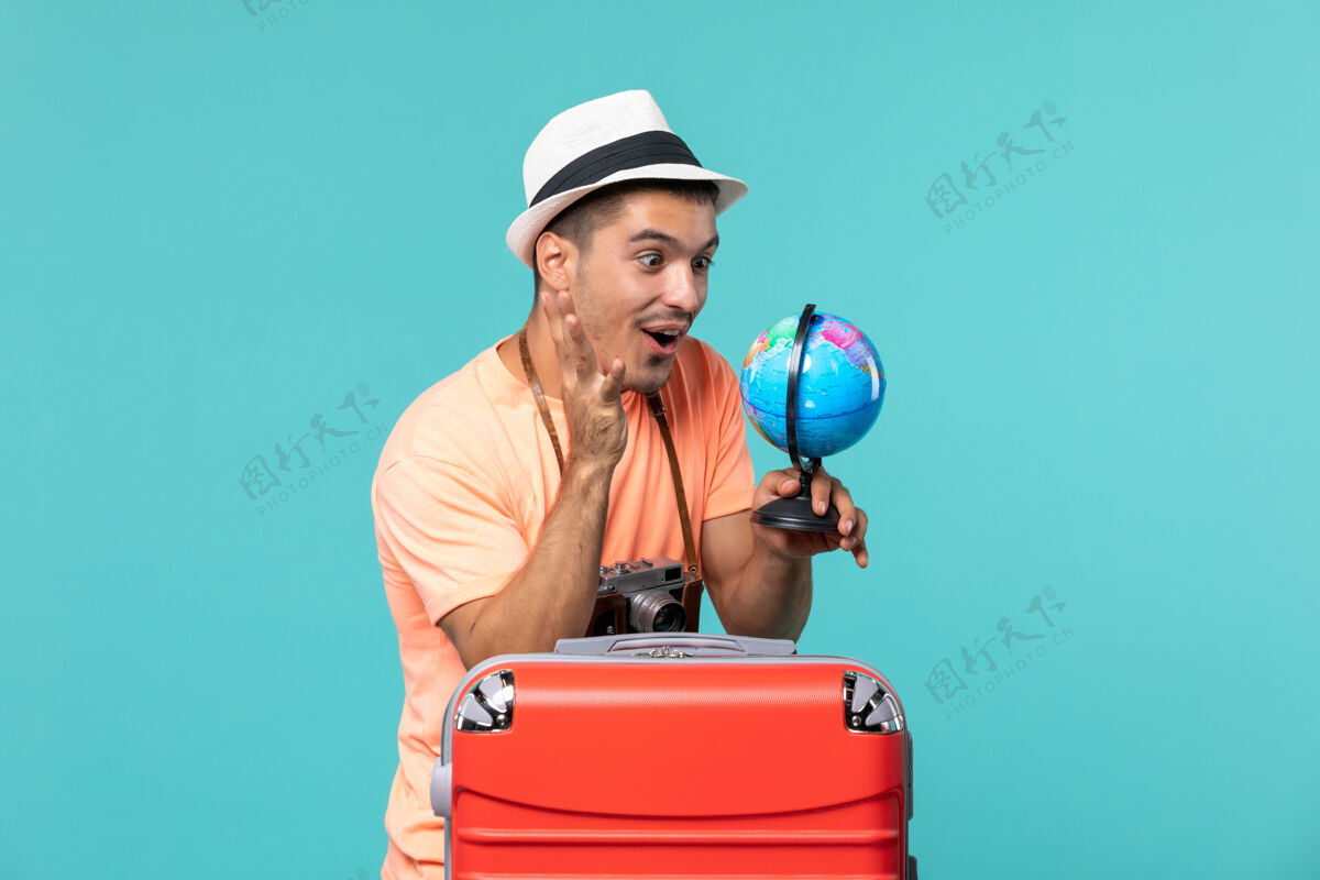 航行度假的男人拿着地球仪用蓝色的相机拍照旅行人旅行