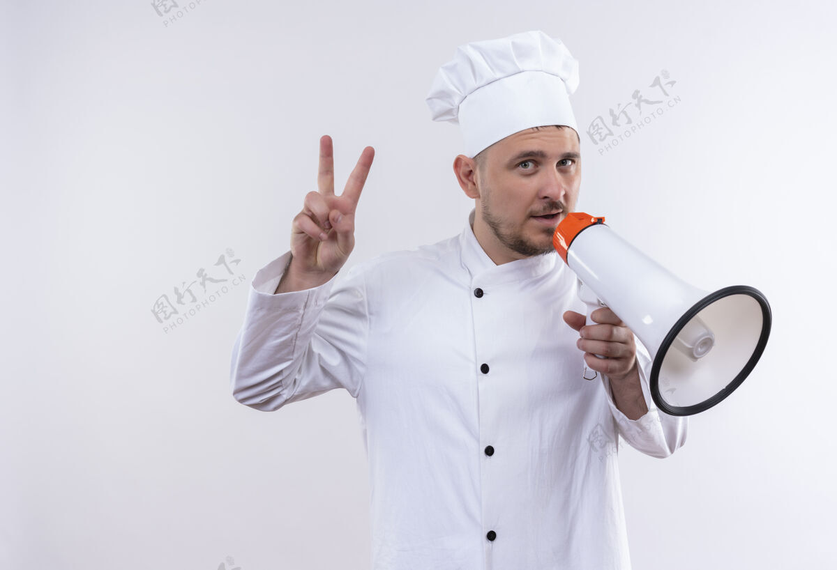 厨师自信的年轻帅哥厨师身着厨师制服 手持扬声器 做着隔离在白墙上的和平标语制服和平厨艺
