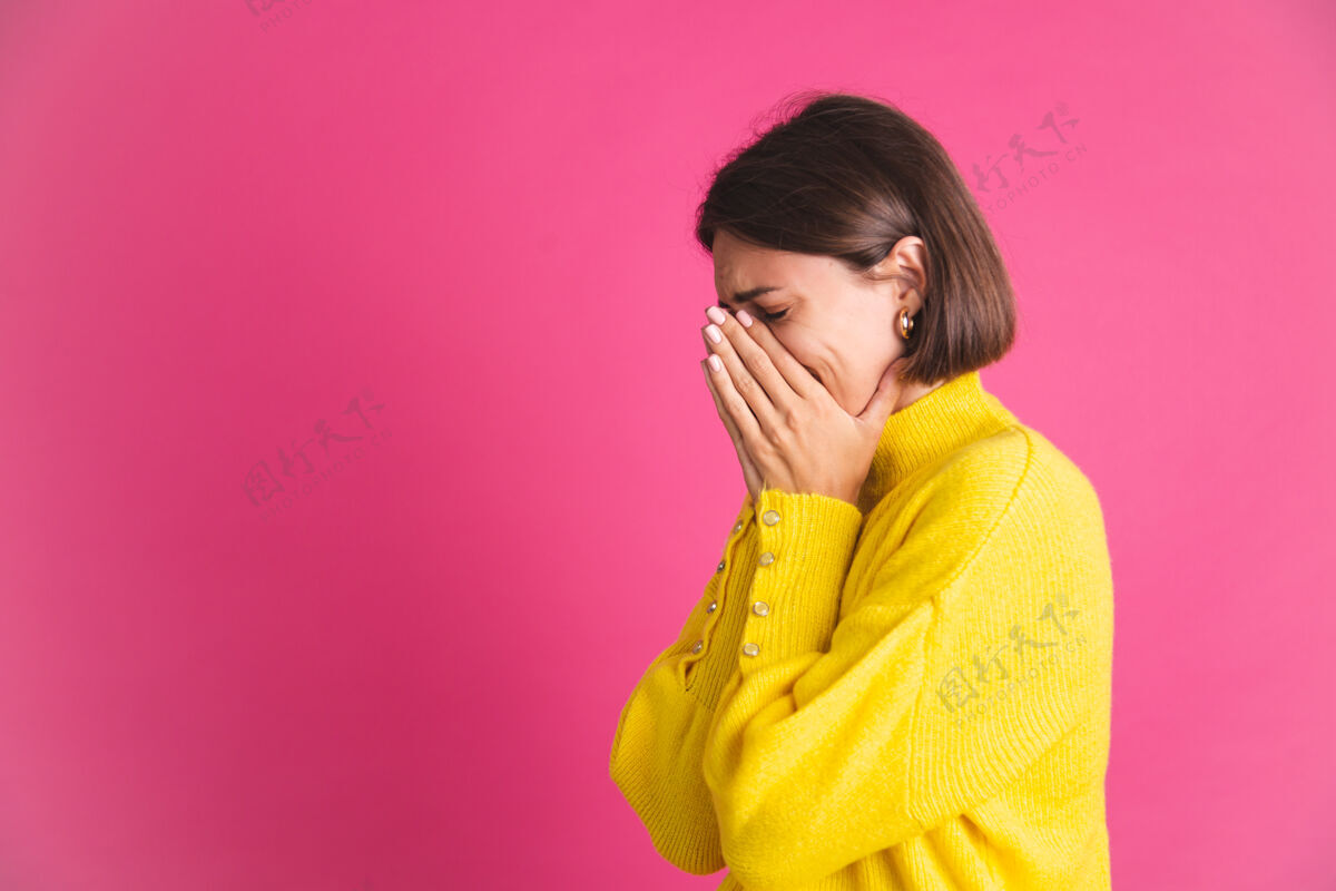 错误美丽的女人穿着亮黄色的毛衣孤立地对着粉色紧张的哭闹抑郁冷静孤独女性
