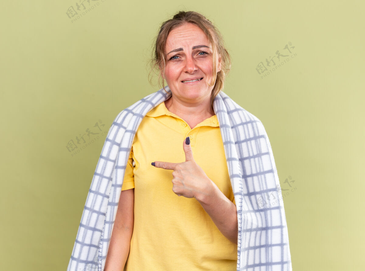 手指不健康的妇女裹着毛毯 感觉不舒服 患流感和感冒 发烧 食指指向绿墙那边发烧壁板目录