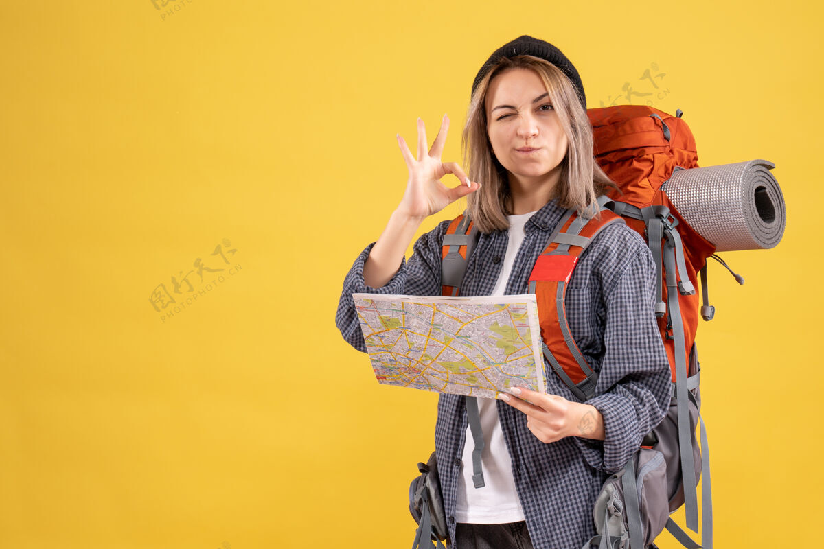 成人一个眨着眼睛拿着地图的女旅行者正在做一个好的标志制造时尚眼睛