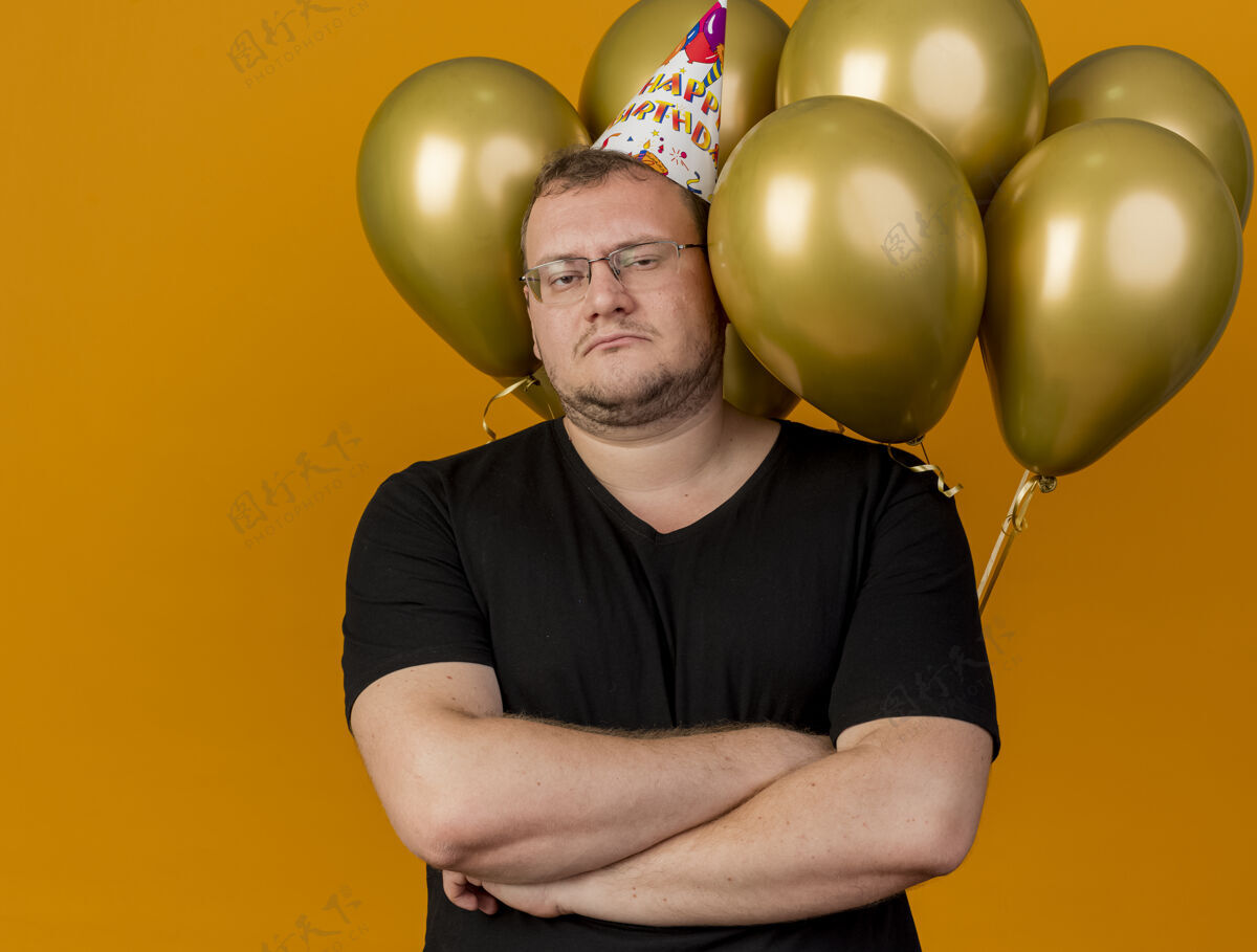 气球自信的成年斯拉夫人戴着生日帽戴着眼镜交叉双臂站在氦气球前穿斯拉夫帽子