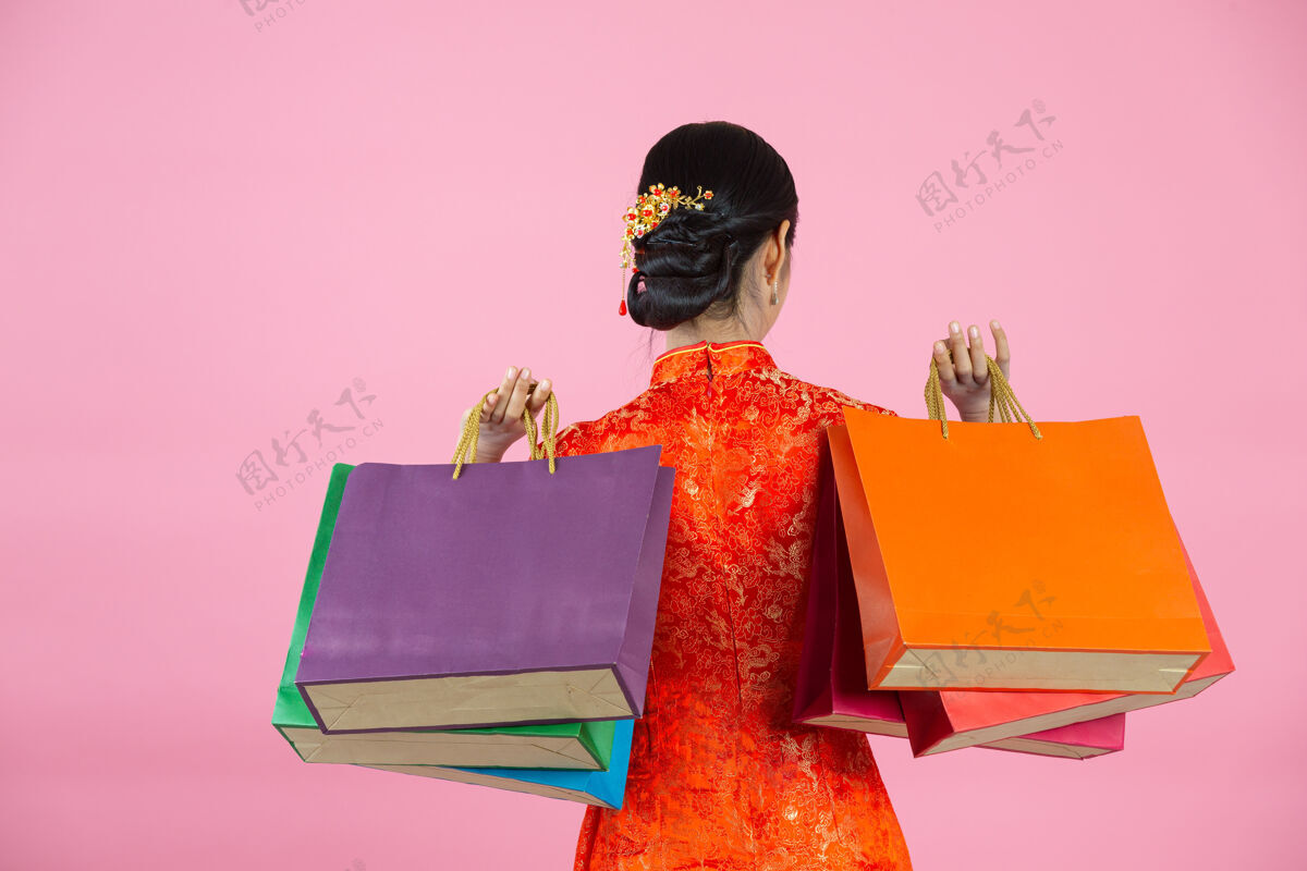 人物美丽的亚洲女人快乐的微笑和购物在中国新年的粉红色背景空白东方女士