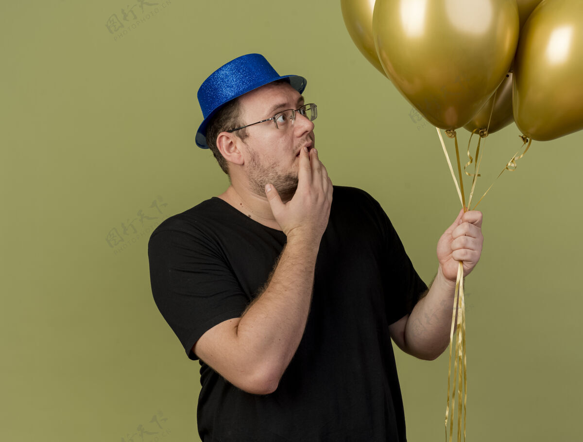 绿色一个戴着眼镜 戴着蓝色派对帽的成年斯拉夫人站在那里看着氦气球帽子眼镜惊喜