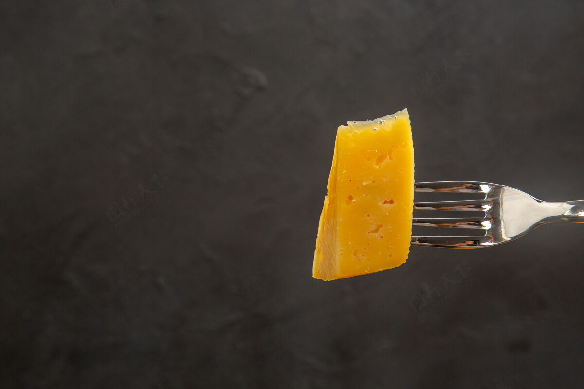 叉子前视新鲜奶酪片叉子深色小吃彩色照片早餐酥脆奶酪前台食物