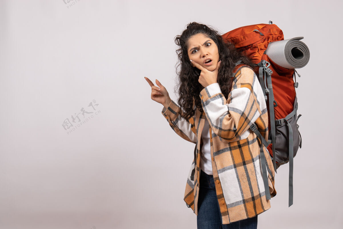 美丽正面图：年轻女子背着背包在白色背景的森林里徒步旅行度假山上航空旅游校园校园伞徒步旅行