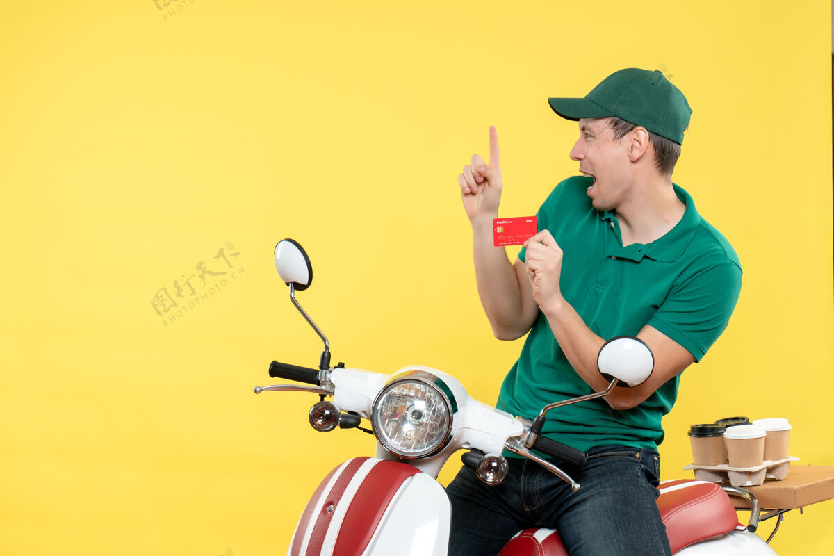速度正面图身穿绿色制服的年轻男性快递员手持黄色银行卡送货制服货舱