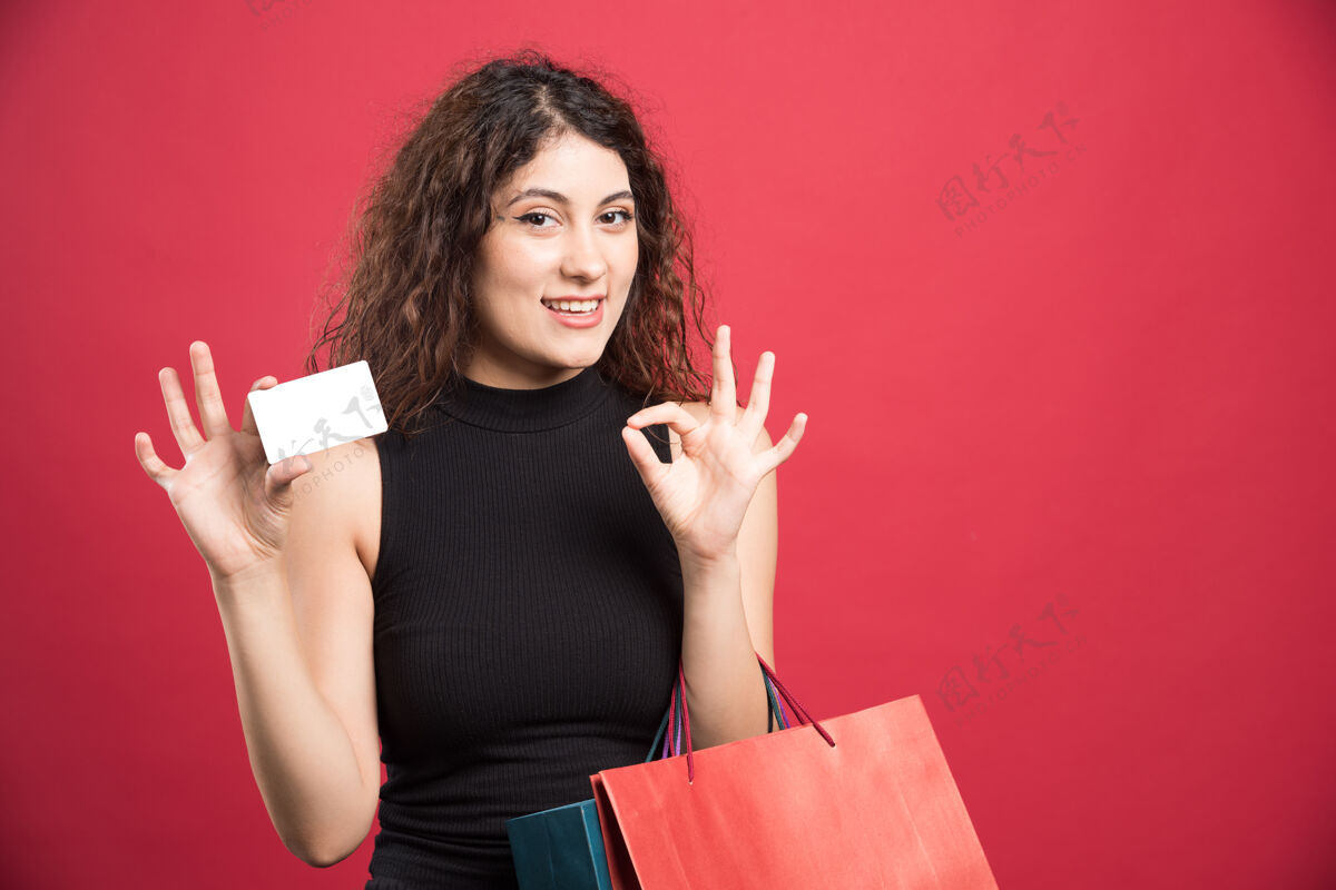 女性快乐的女人带着许多包和银行卡上的红色银行卡购物狂衣服