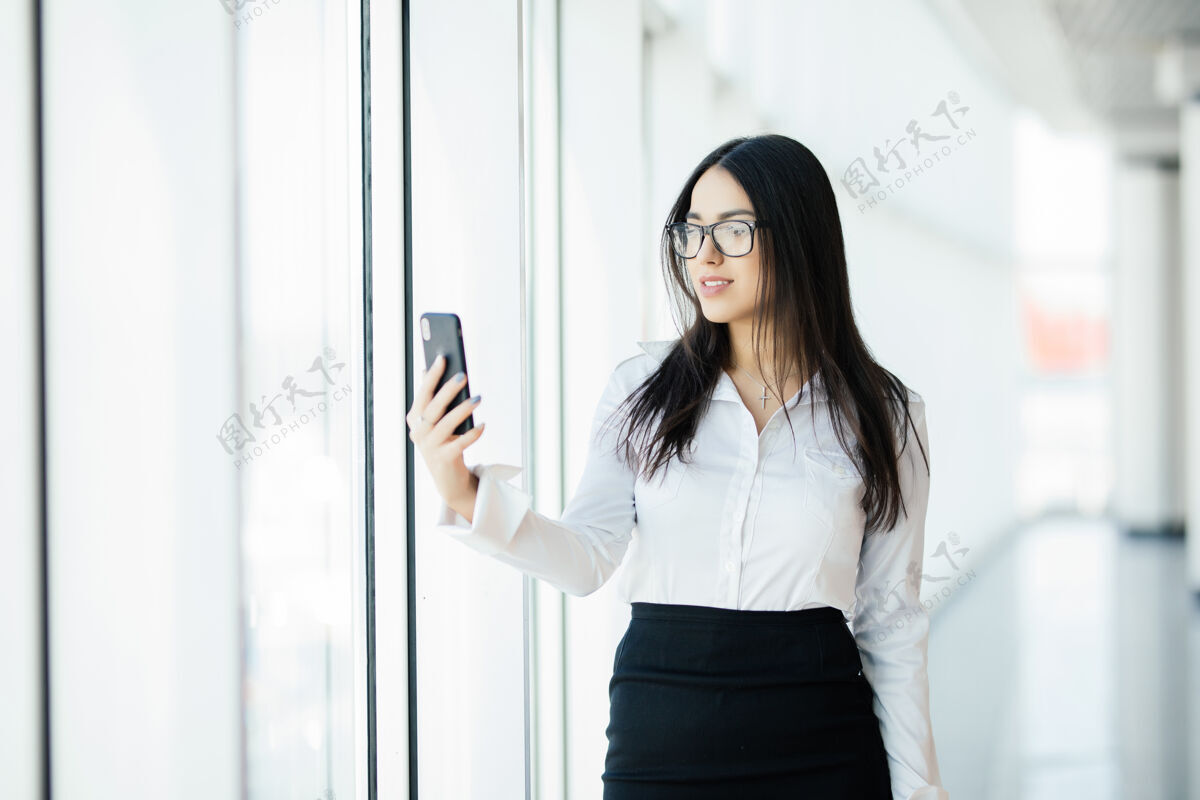 公寓美女在全景窗口使用手机商业理念漂亮肖像金融