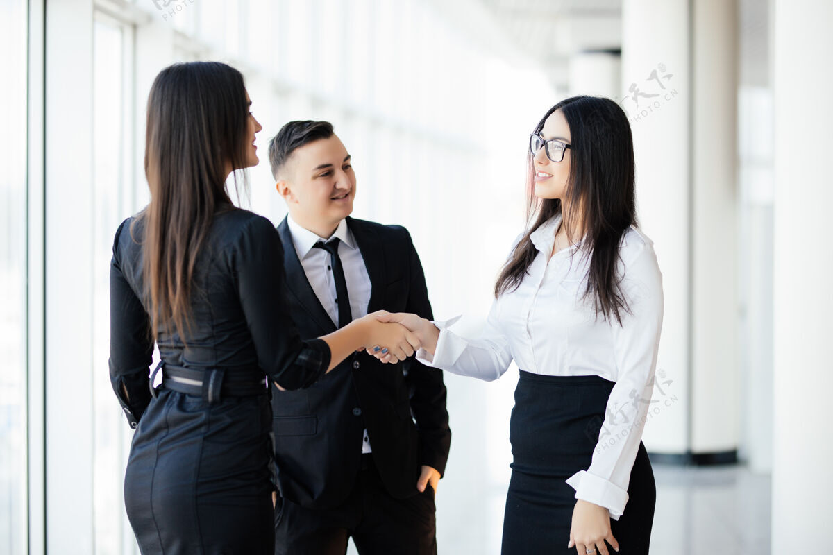 销售人员商务伙伴在会场握手两位商务女士在办公室握手致意合作伙伴握手小组