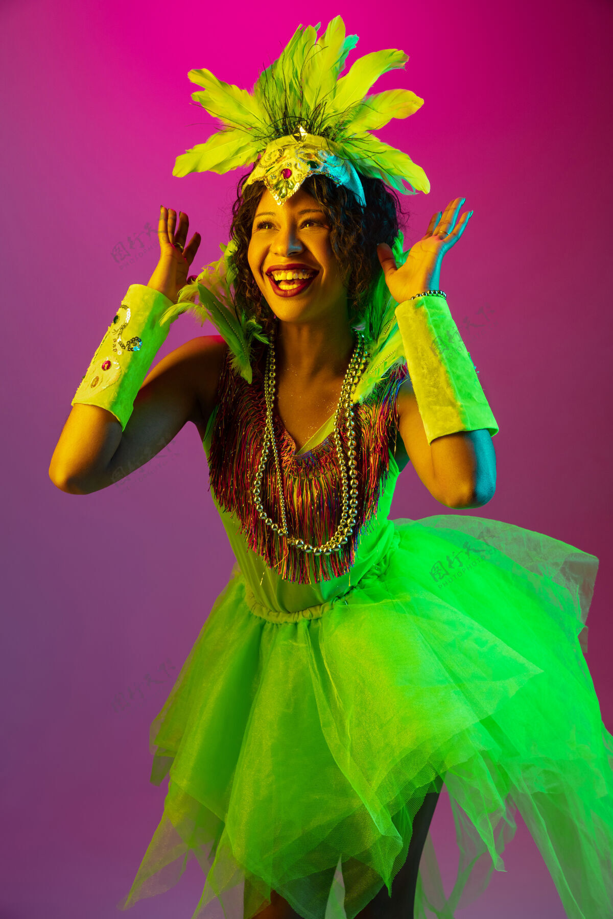肖像美丽的年轻女子在狂欢节 时尚的化装舞会服装与羽毛跳舞的梯度墙上霓虹灯人类剧院面具