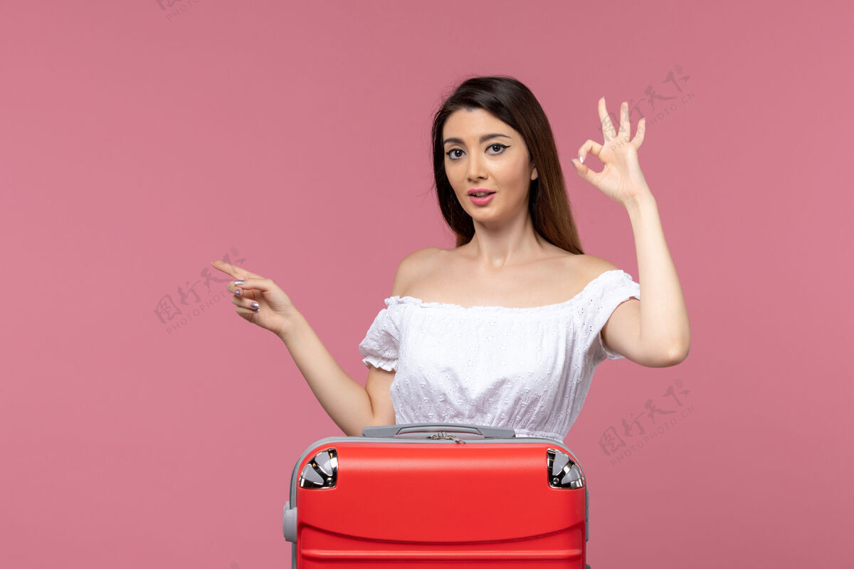 包正面图：年轻女性带着她的红色袋子准备度假 背景是粉色的出国旅行和海上旅行旅行人成人