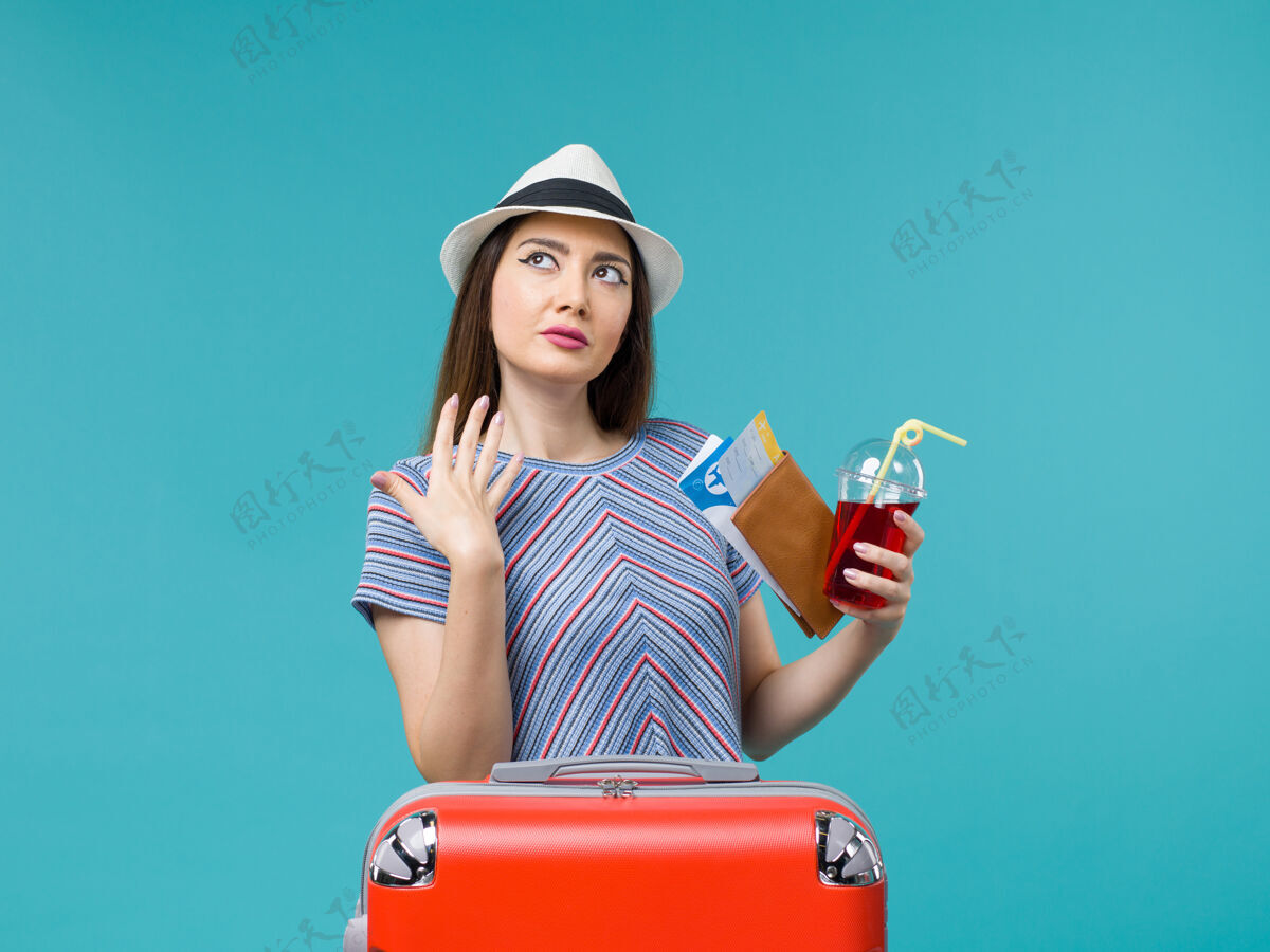 旅程前景度假中的女人拿着果汁拿着蓝色背景上的机票航行旅程女海飞机夏天人肖像果汁