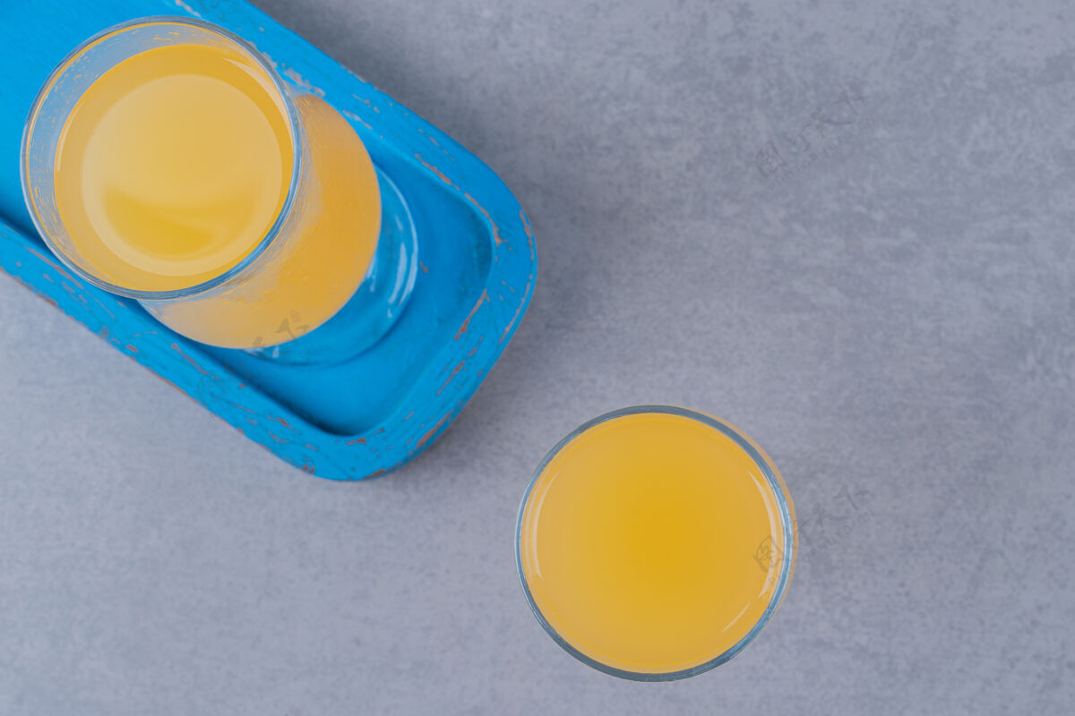 健康蓝色木板上新鲜橙汁的俯视图深色不含酒精草药