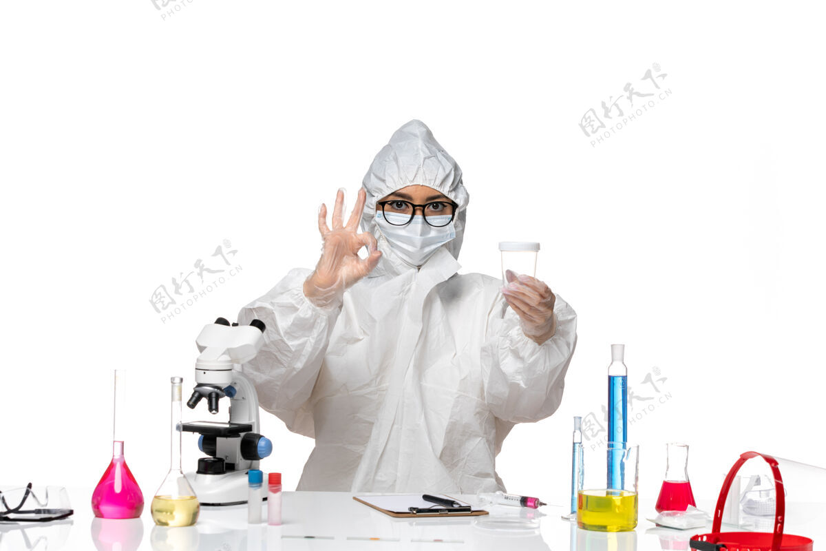 套装正面图身穿特殊防护服的年轻女化学家拿着浅白色背景上的空烧瓶实验室冠状病毒-化学病毒保持面罩药