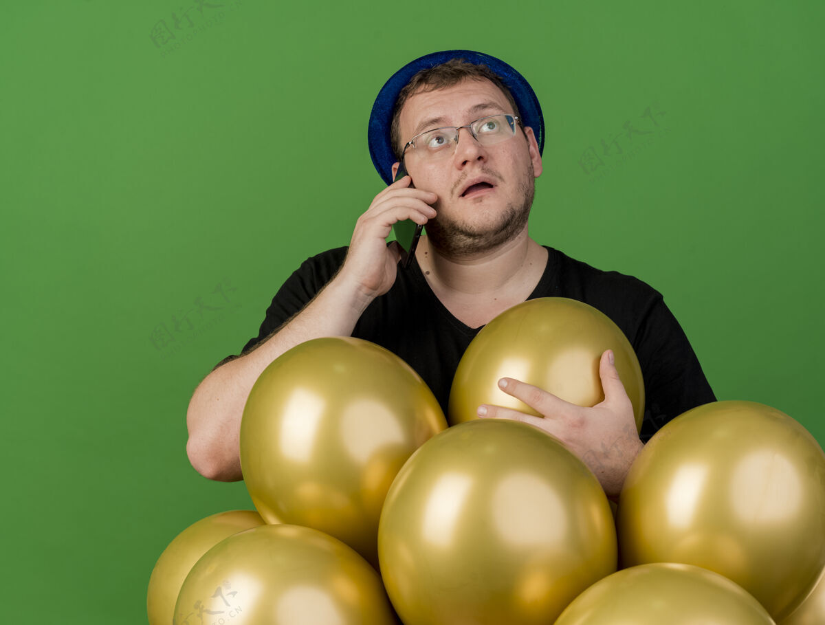 男人令人印象深刻的成年斯拉夫人戴着眼镜戴着蓝色派对帽拿着氦气球打电话气球绿色成人
