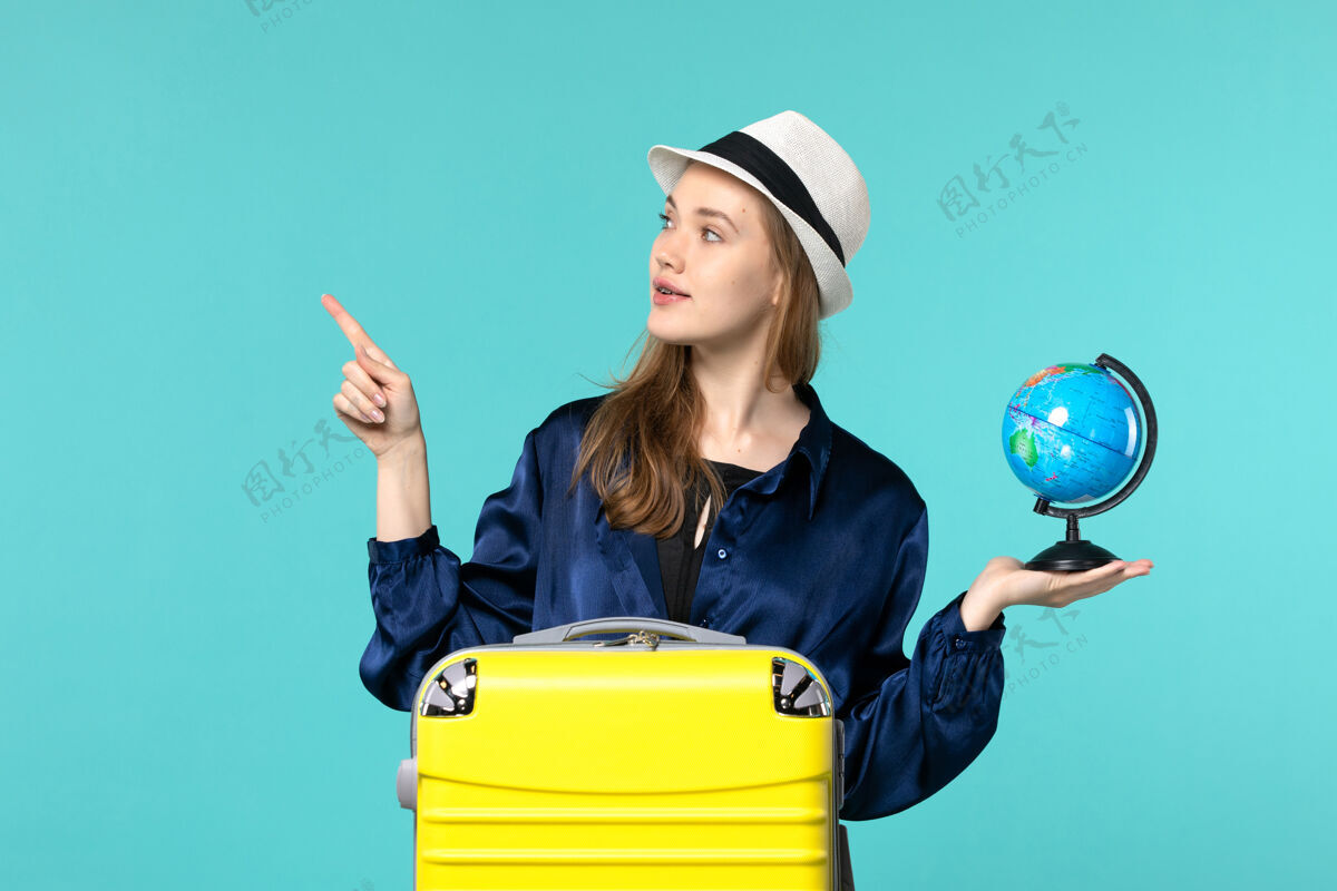 旅程前视图年轻女子拿着地球仪 准备在蓝色背景上度假女性度假旅行航海飞机手持旅程年轻女子