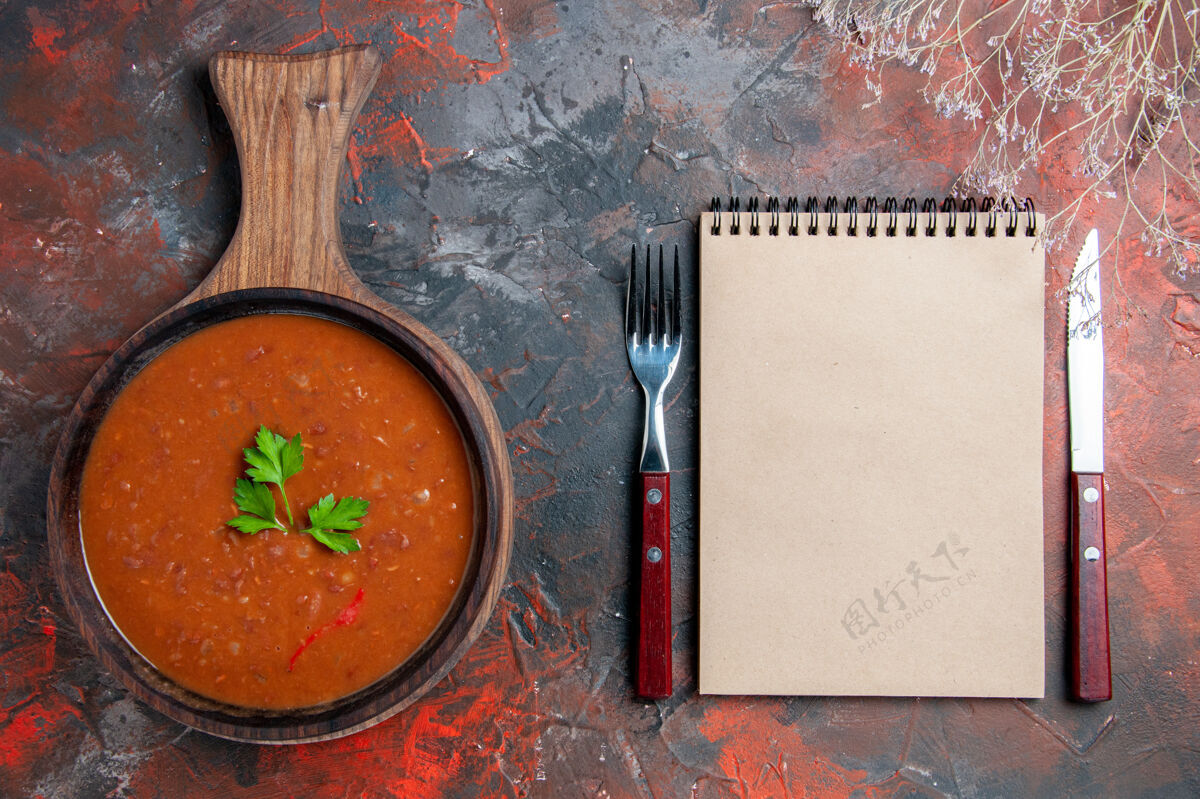 混合在棕色砧板和混合色背景上的笔记本上俯瞰经典番茄汤黑板背景西红柿汤