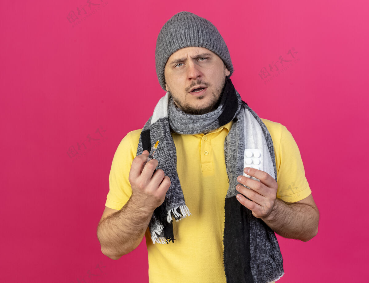 围巾无知的年轻金发病斯拉夫男子戴冬季帽子和围巾持有注射器药丸金发年轻人