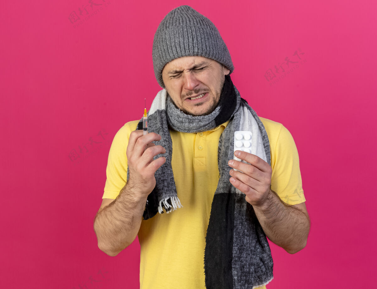 注射器年轻的金发病斯拉夫男子戴着冬季帽子和围巾拿着注射器男人药丸围巾