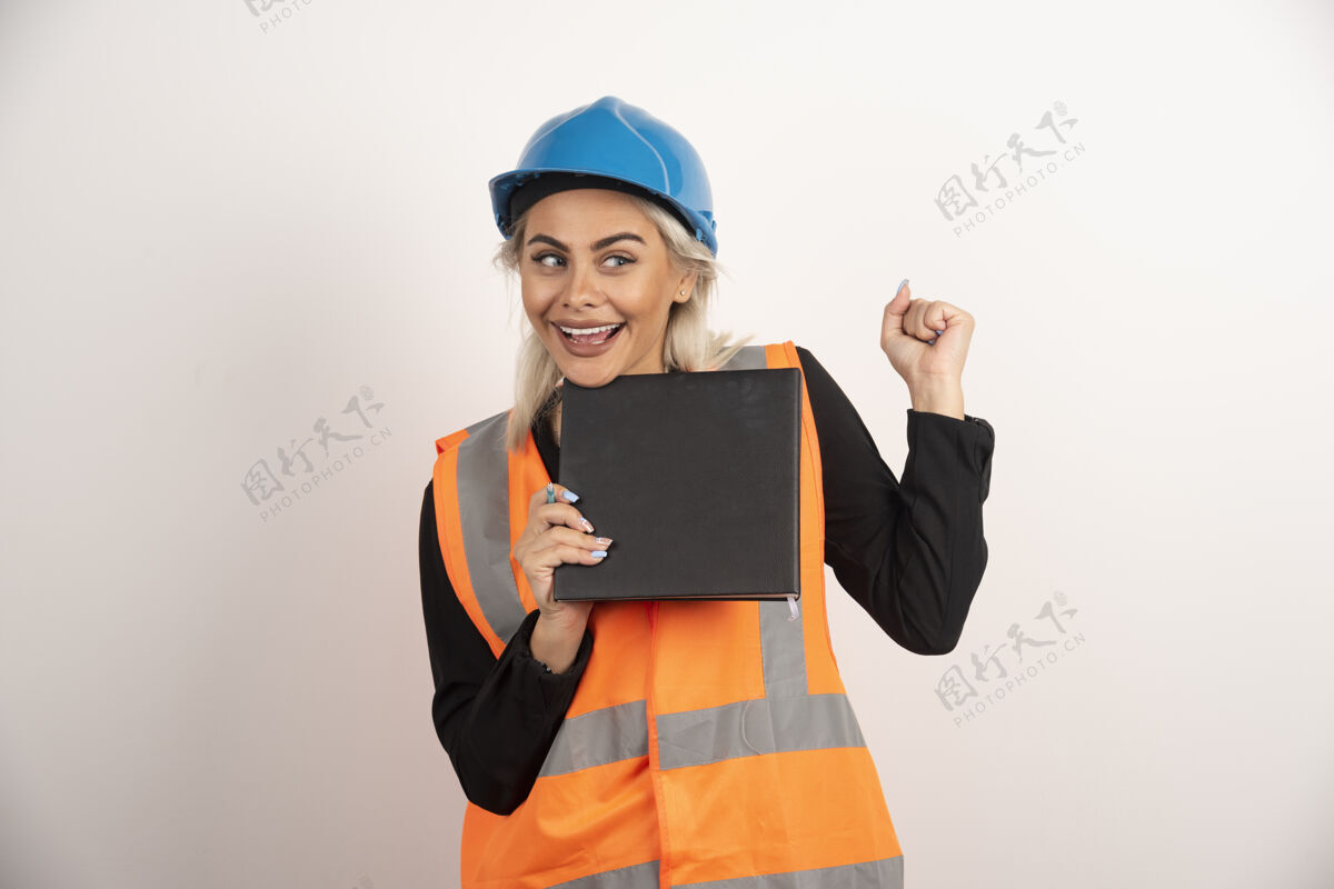 人面带微笑的工人拿着笔记本站在白色的背景上高质量的照片姿势安全帽工程师