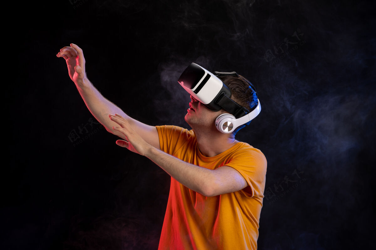 成人年轻人戴着虚拟现实耳机在黑暗的表面幻想黑运动