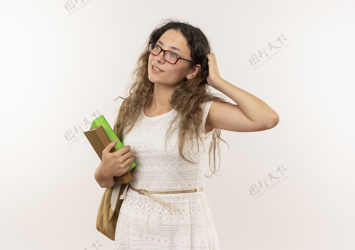 感觉体贴的年轻漂亮的女学生戴着眼镜 背着书包 手放在头上 看着隔离在白墙上的一面包姿势手