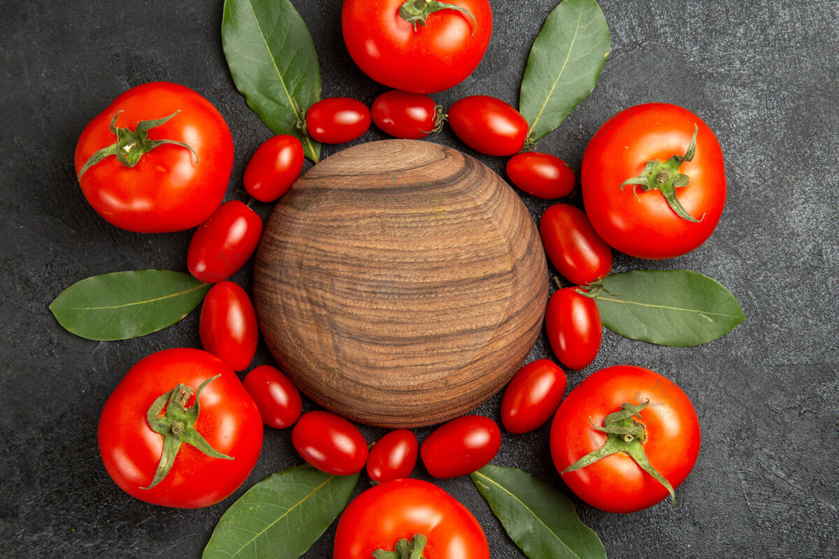 食物俯视图樱桃和红色的西红柿在黑暗的地面上围绕着一个木制的盘子沙拉木头盘子