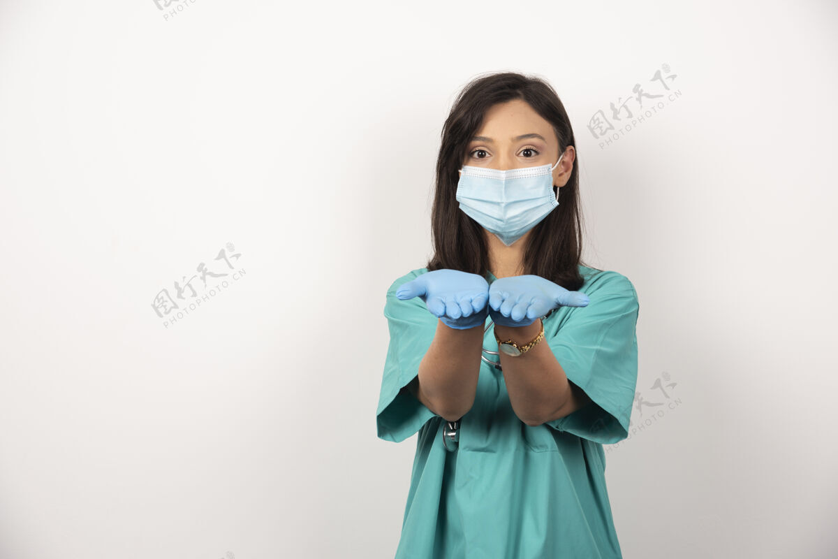 工作戴着医用面罩和手套的年轻医生在白色背景上张开双手高质量照片妇女女性健康