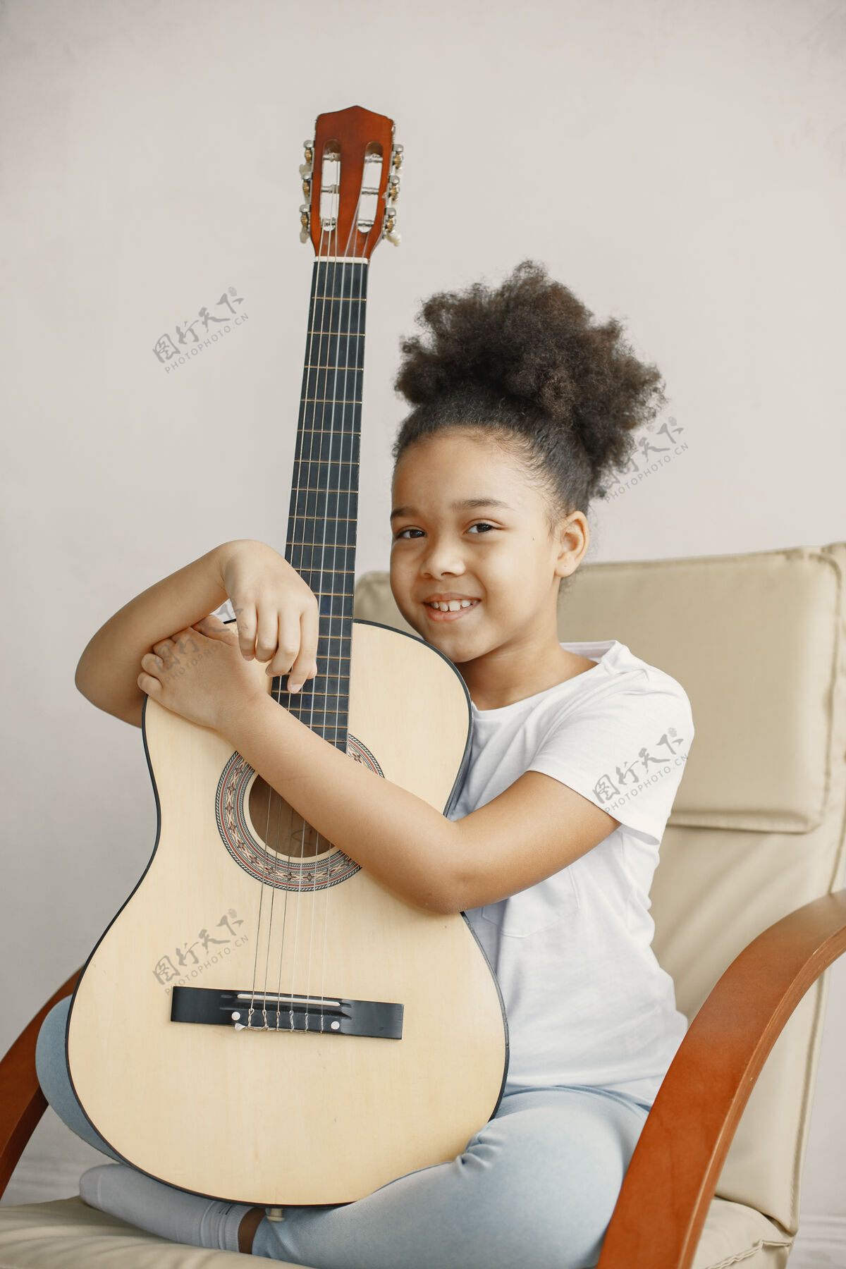 女孩卷发的小女孩学弹吉他坐在椅子上的小女孩肖像欢呼椅子