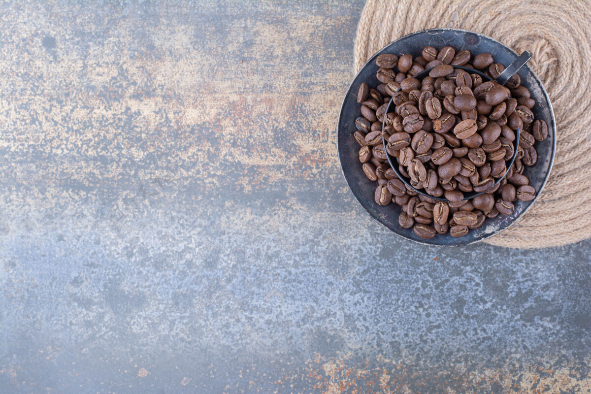 马克杯在大理石上放满咖啡豆的黑杯子美味浓缩咖啡自然