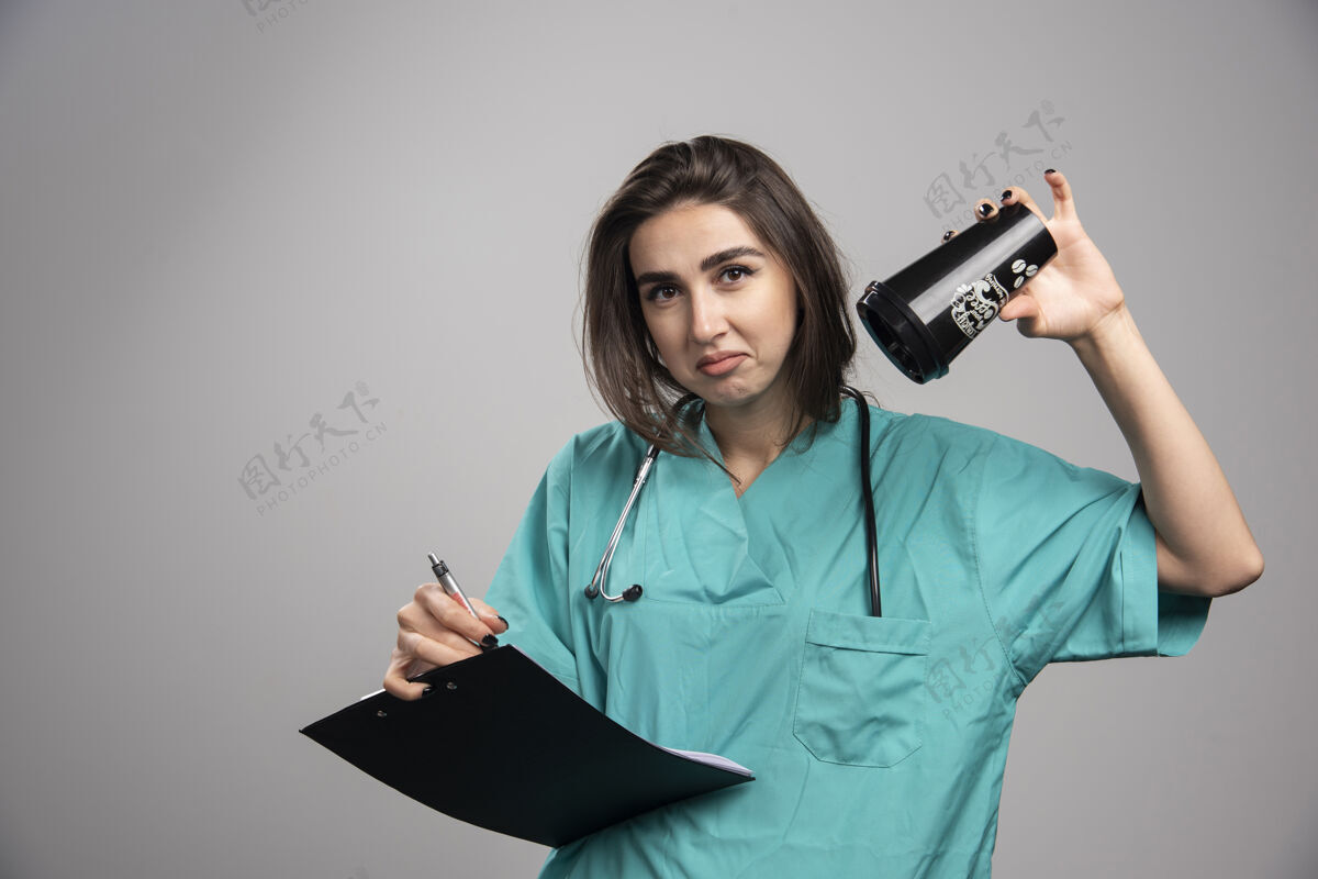 护理年轻医生拿着杯子和剪贴板在灰色背景上高质量的照片疾病个人成人