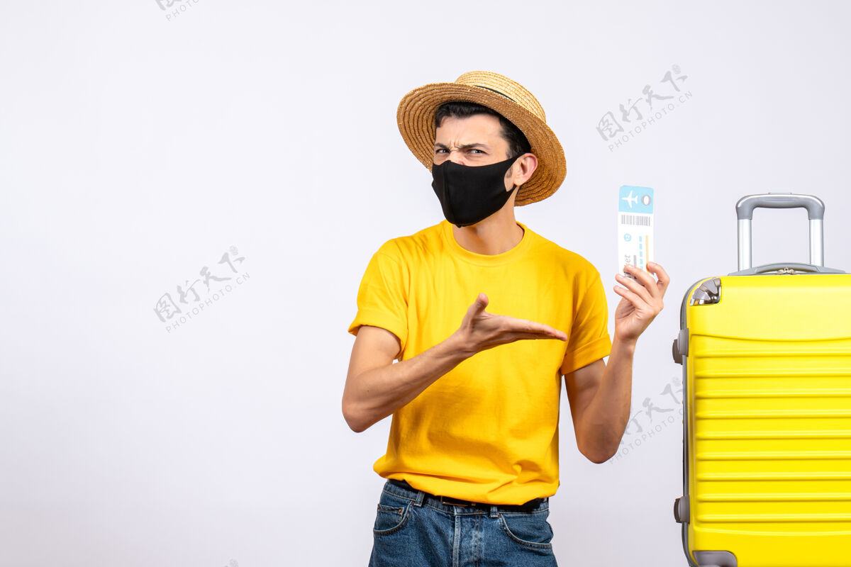 黄色正面图穿着黄色t恤的年轻人站在黄色手提箱旁指着机票男人站T恤