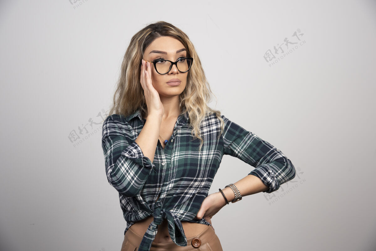 衬衫一个戴着眼镜的年轻漂亮女人的肖像画被隔离在灰色背景墙上肖像头发眼镜