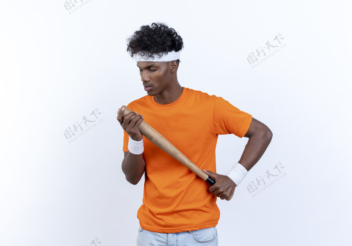 背景闭着眼睛的年轻的美国黑人运动男子戴着头带和手环拿着球棒持有男人眼睛