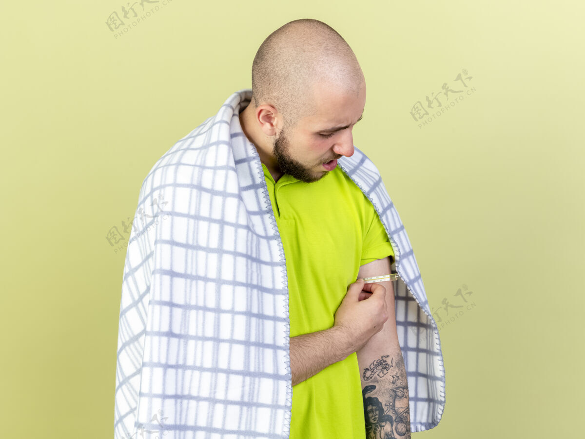 年轻年轻的病人裹着格子布 拿着隔离在橄榄绿墙上的温度计测量温度人表情包裹